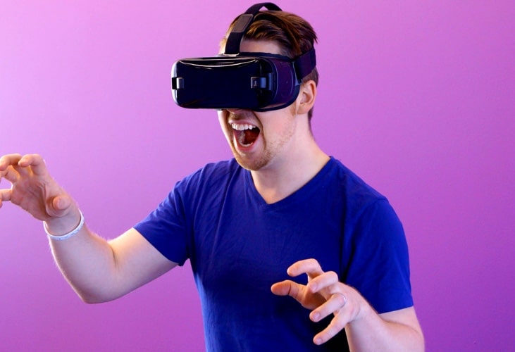 an individual wearing a virtual reality (VR) headset, interacting with a virtual environment. The background is a plain purple color.